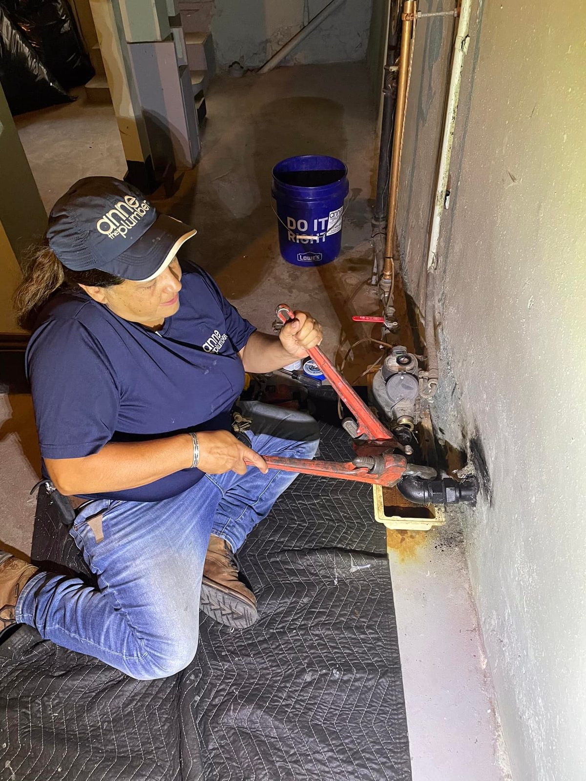 Anne the Plumber fixing a pipe on a job site in Rhode Island