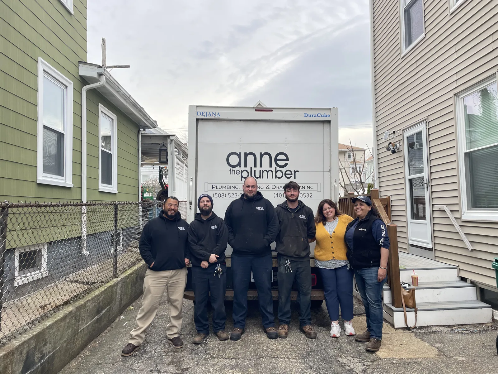 The Anne the Plumber team in front of the service truck — driveway angle